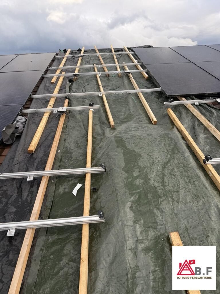 Bâchage de toiture en urgence à Borex dans le canton de Vaud avec bâche de protection sous panneaux solaires pour éviter les infiltrations d’eau.